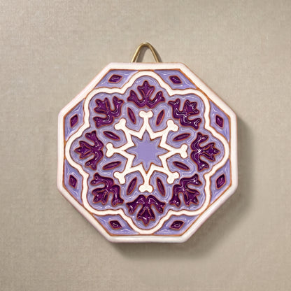 Vista frontal completa del plato decorativo de pared octagonal en relieve Estrella Amatista, pintado a mano con geometría andalusí en tonos lila, violeta, blanco y detalles en bronce Kinara.